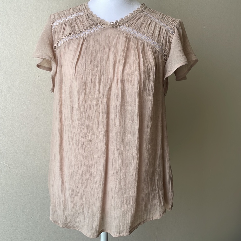 Nude color blouse with ruffles on the sleeves.